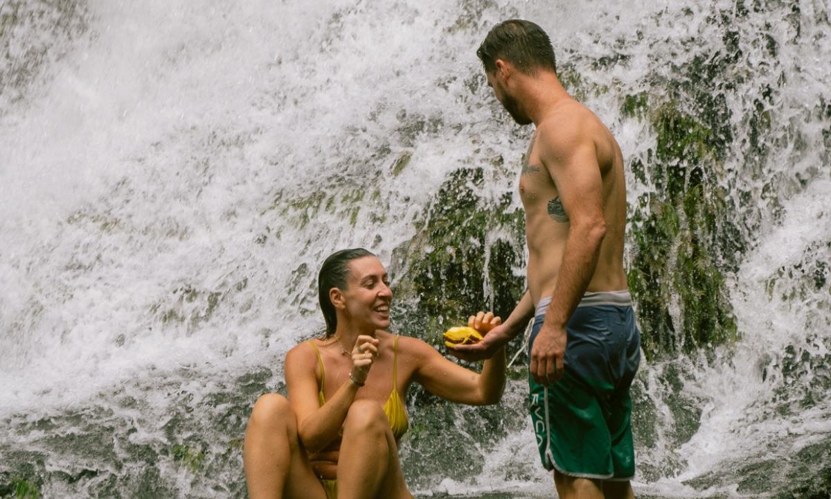 Couple sharing fruit at hidden waterfall